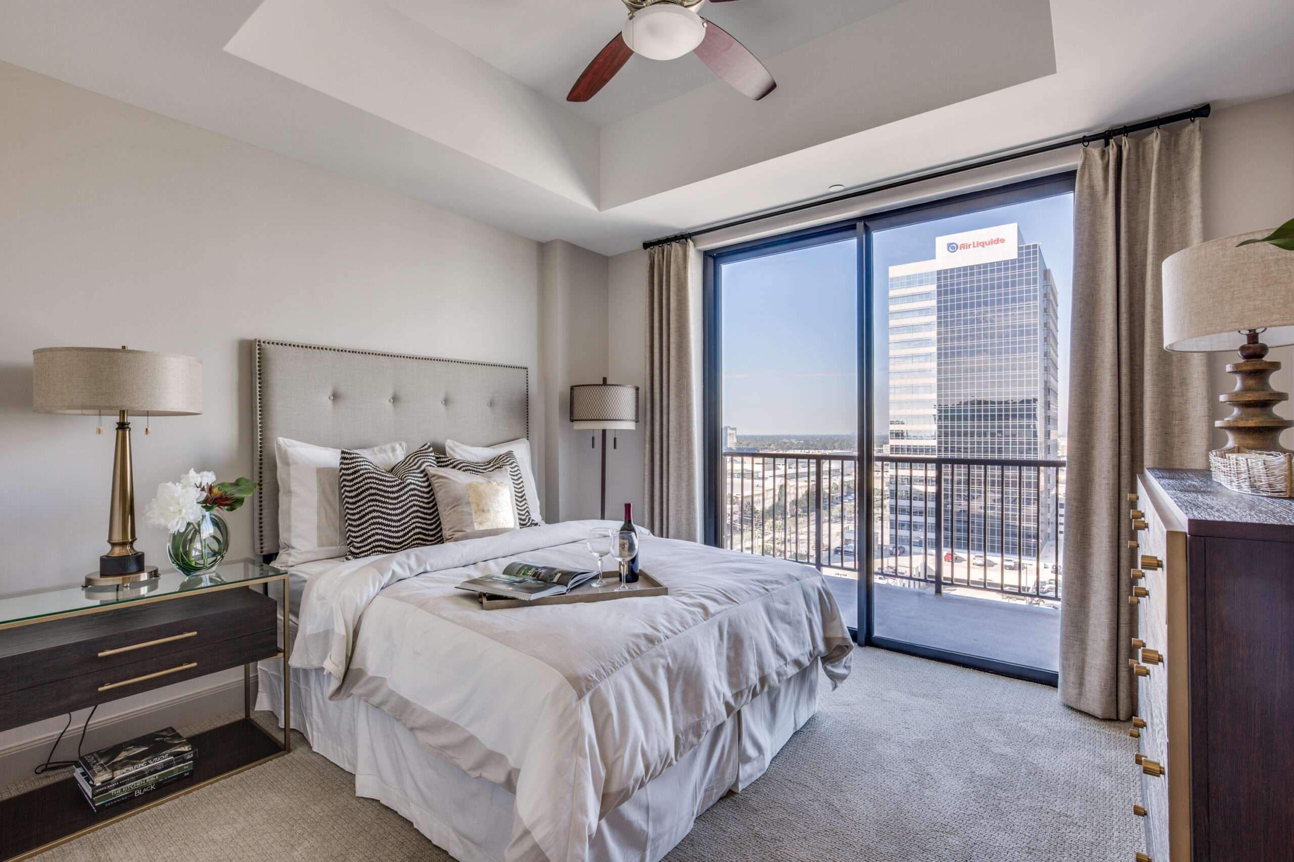 Bedroom at The McCarthy with an upholstered headboard and a balcony overlooking the city