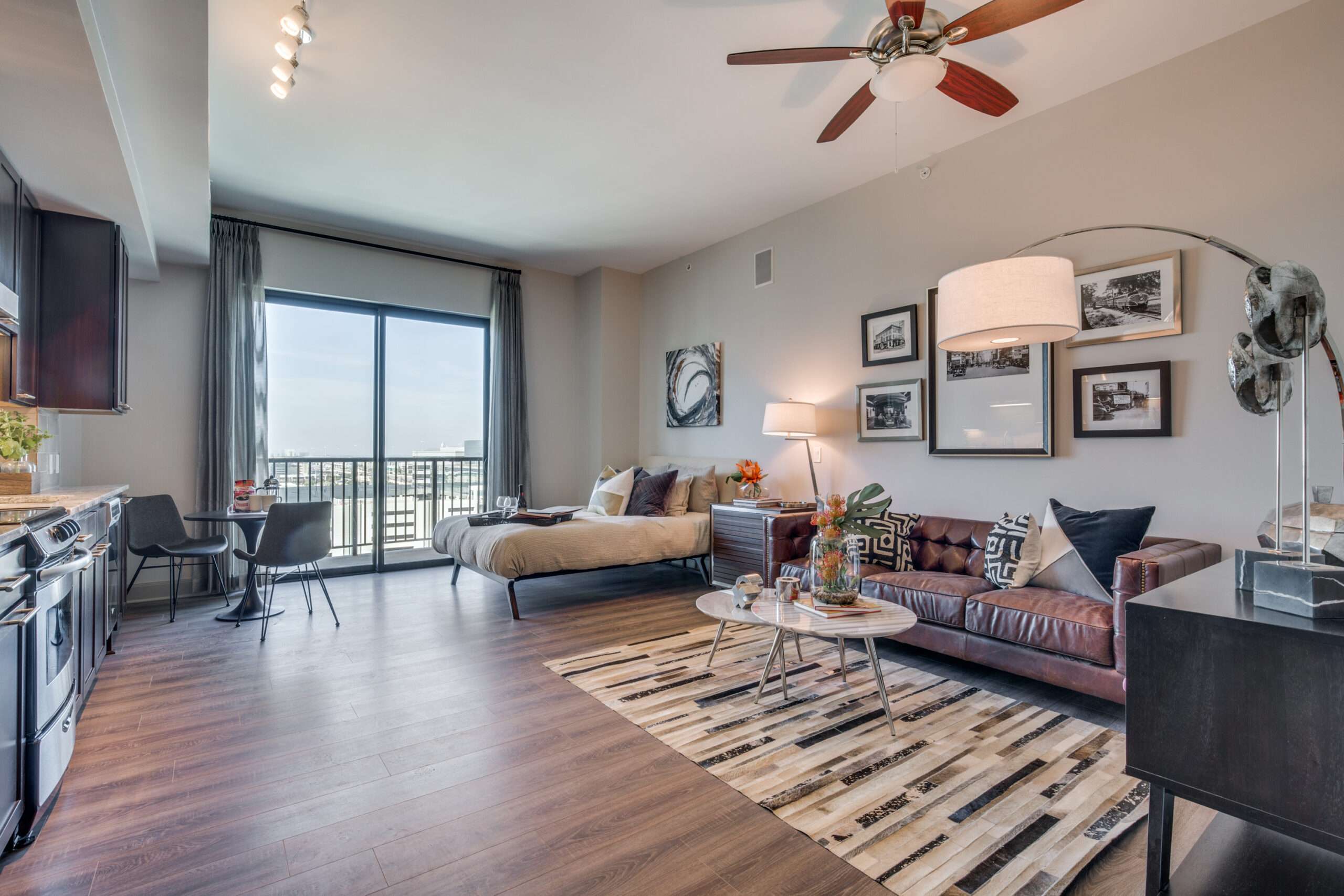 Studio apartment at The McCarthy with a bed, sofa, kitchen and balcony door
