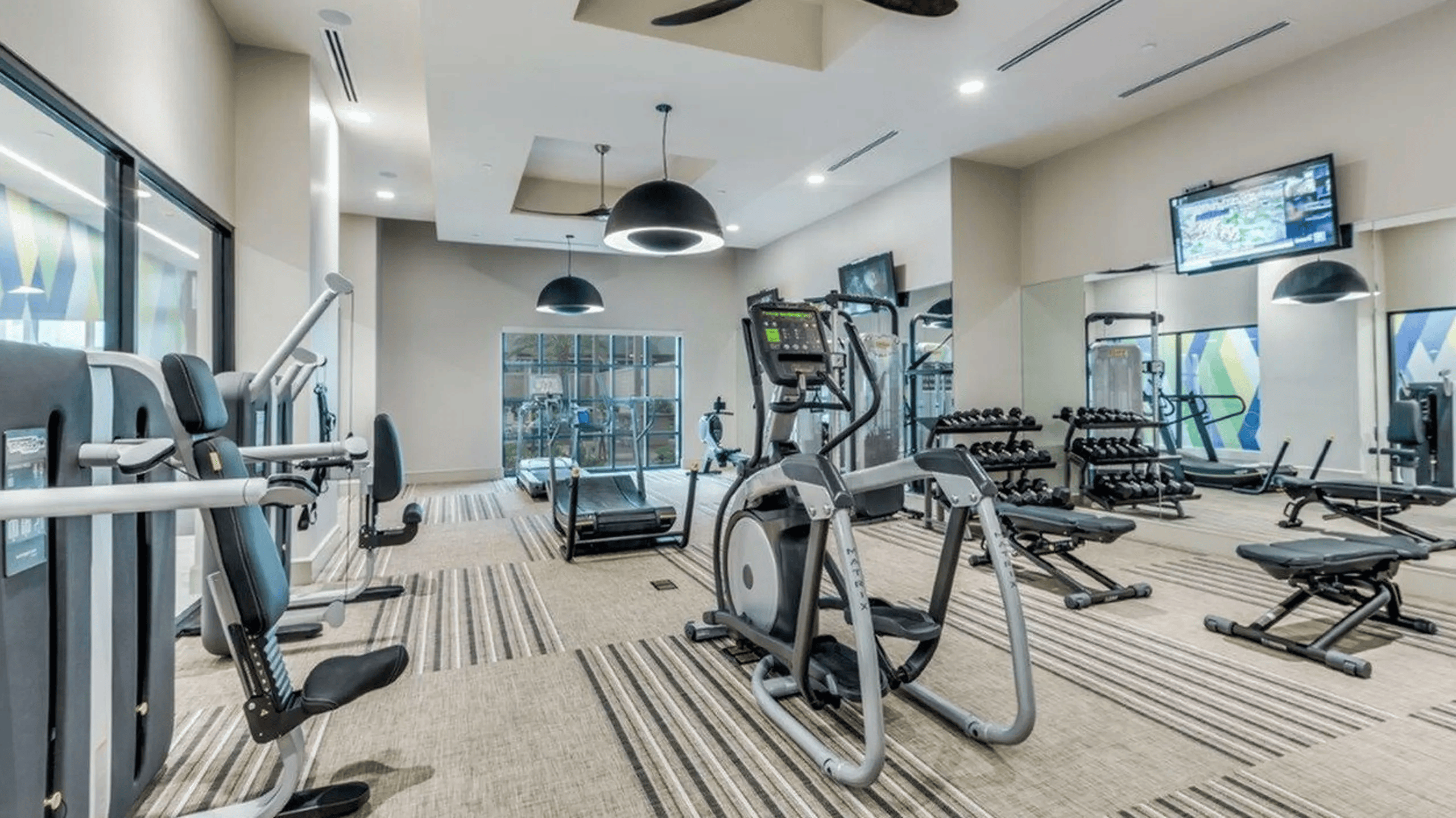 05_Amenities-Card1_Fitness Fitness center at The McCarthy with cardio equipment, free weights and a mirrored wall
