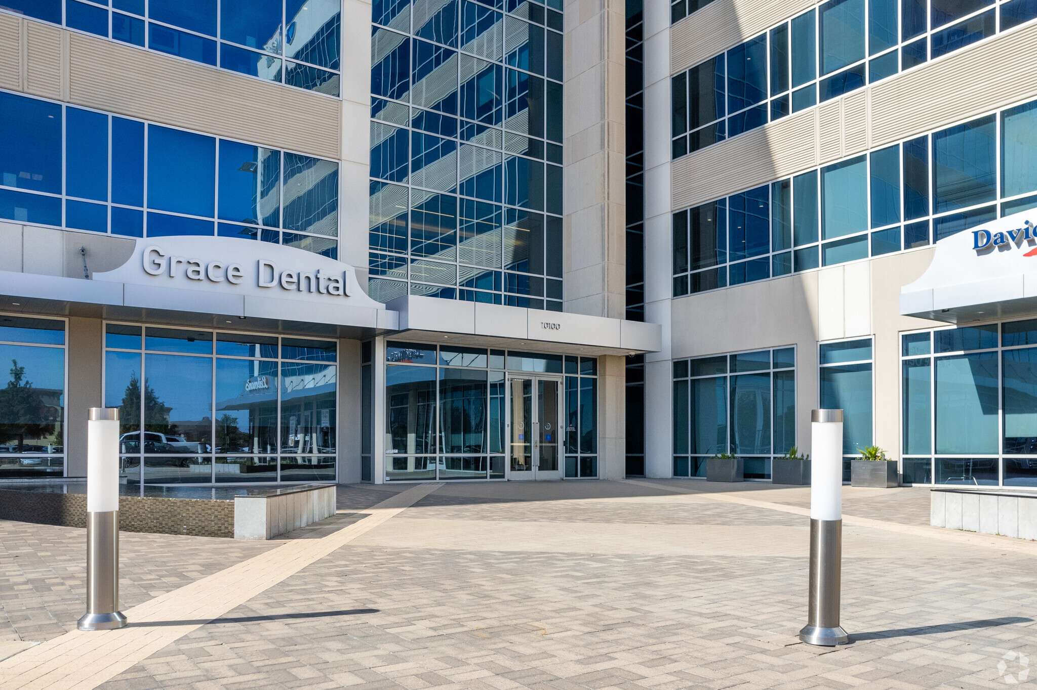 Glass facade and entrance of 10100 Katy Freeway with Grace Dental and David Weekley Homes tenant signage