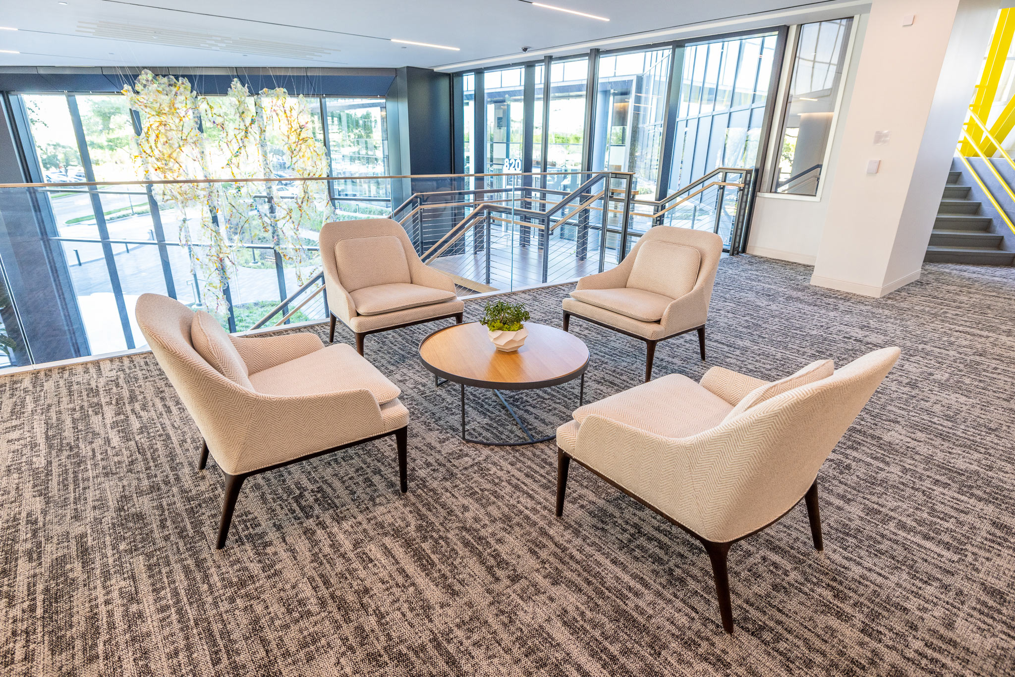 Lobby lounge at 800 Gessner Road with cream armchairs around a round table on patterned carpet