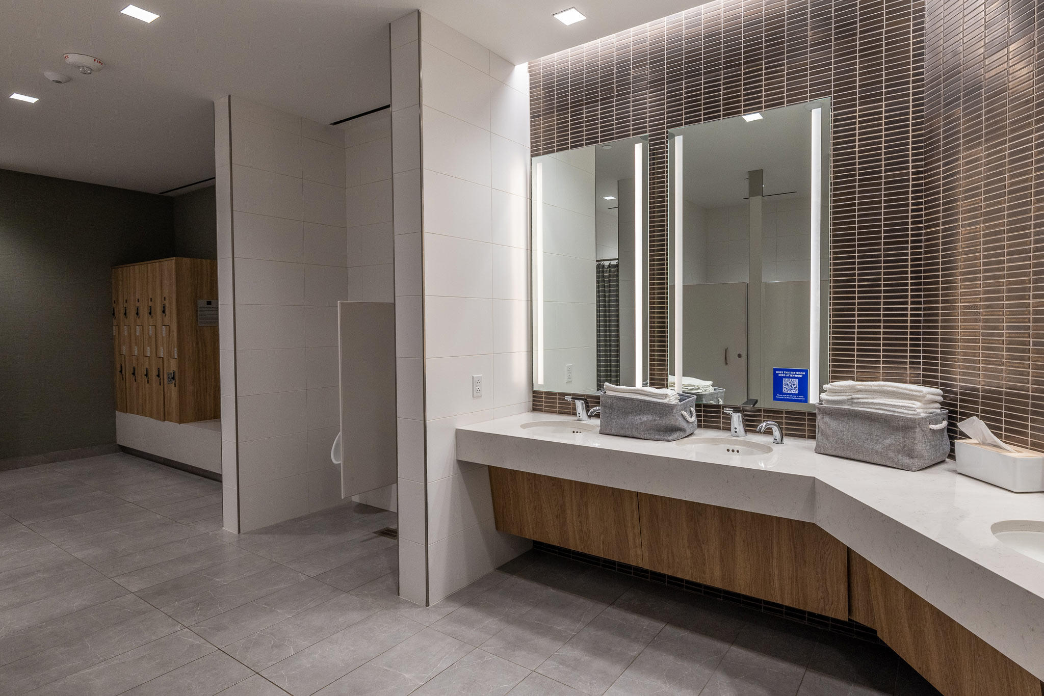 Restroom at 800 Gessner Road with a curved vanity, large mirror and textured wall tile