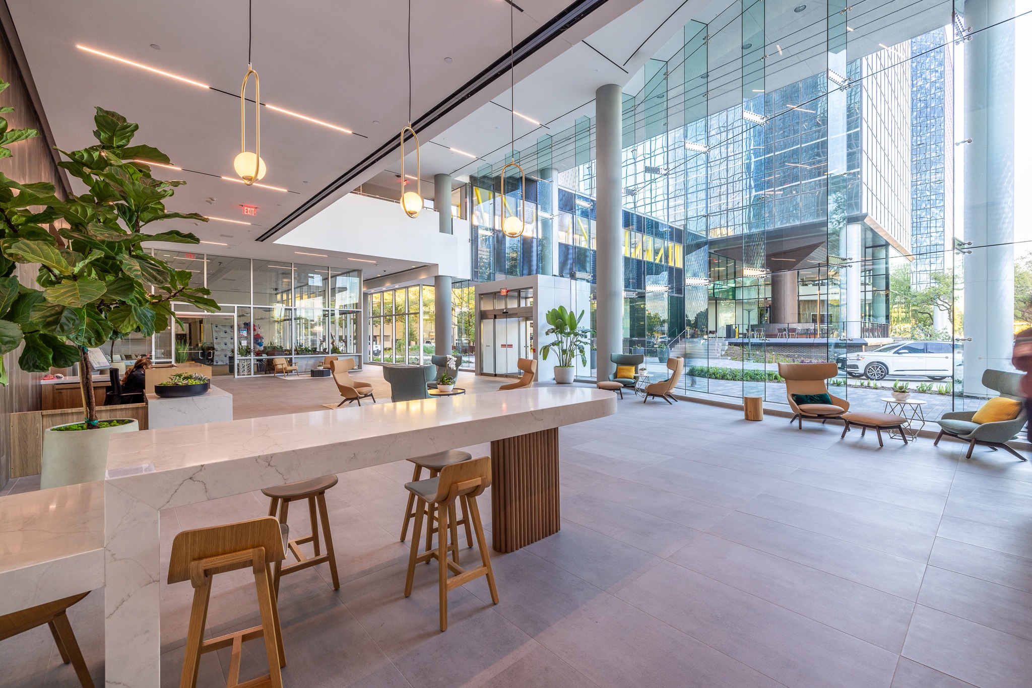Cafe counter with wood stools in the lobby of 840 Gessner Road, beside a glass curtain wall