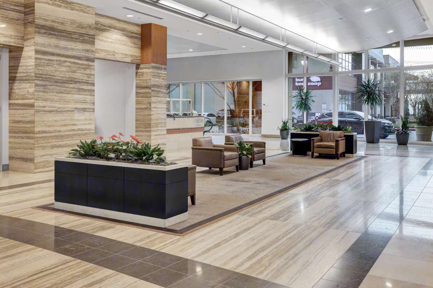 Lobby corridor at 929 Gessner Road with stone-clad columns, planters and seating