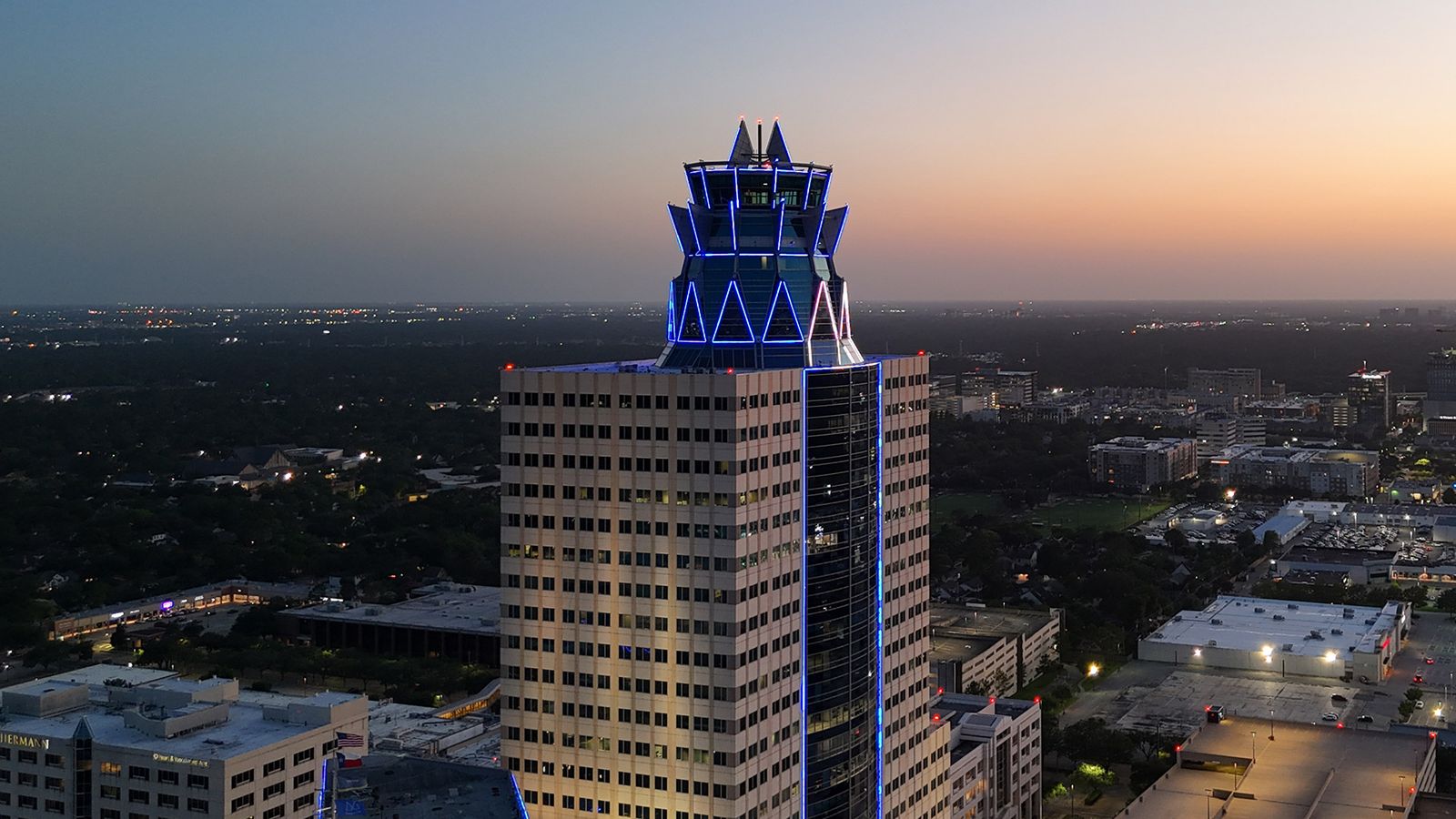Blue-lit crown of Memorial Hermann Tower at 929 Gessner Road against the night skyline