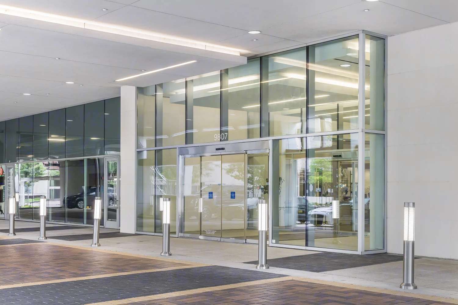 Glass entrance vestibule at Air Liquide Center North, flanked by bollard lights