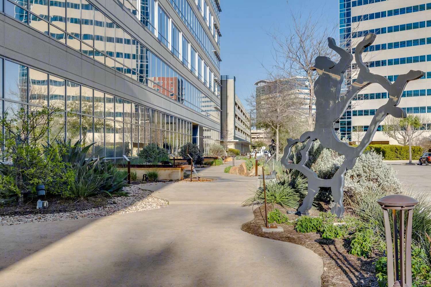 Landscaped walkway beside Air Liquide Center South with sculptural bare-branch artwork