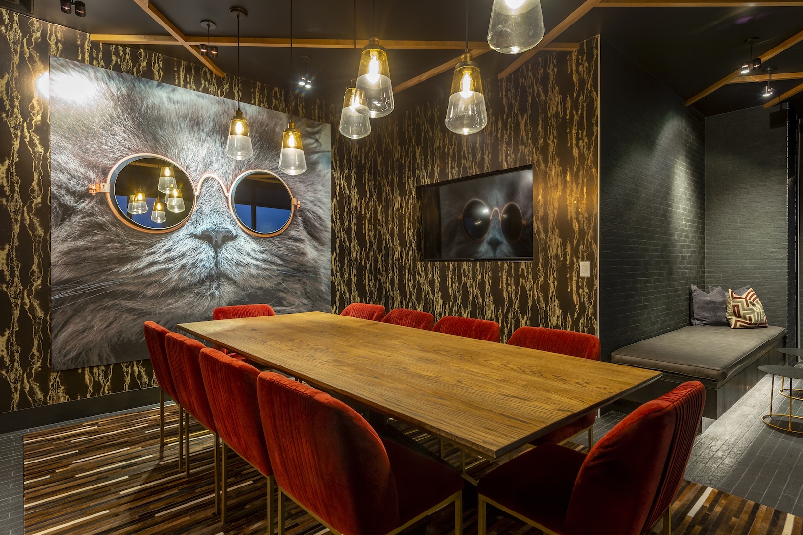 Conference room at The McAdams with a large cat mural, red velvet chairs and a live-edge wood table