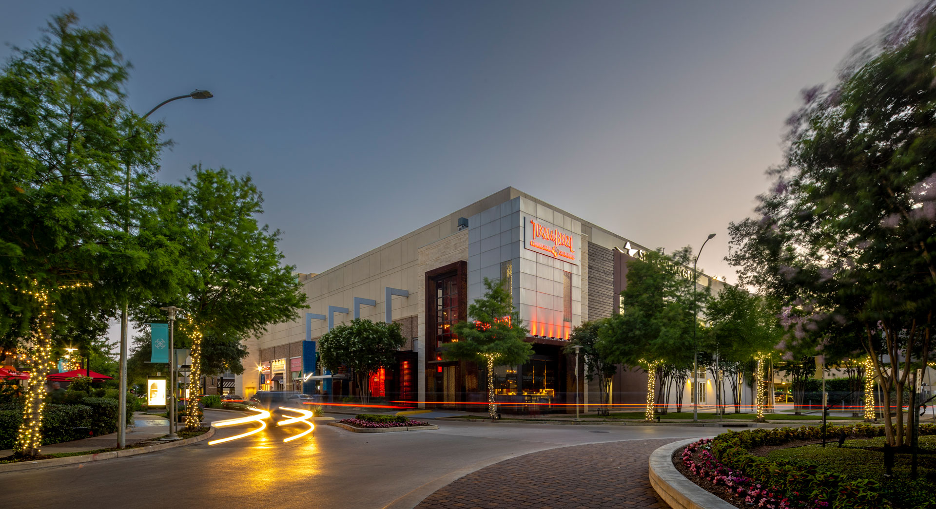 Retail building at CityCentre at dusk, with lit signage and traffic light trails