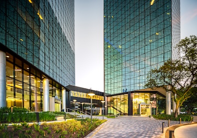 Gessner 800, 820, 840 - Houston, TX 051823 Illuminated lobby and landscaped entrance of the Gessner Road office buildings at dusk