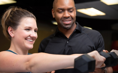 Gateway_MHRSportMed_Rehab A trainer assisting a woman lifting a dumbbell in a fitness center