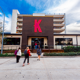 Greenside-Epic-Happy-Hour Pedestrians walking past a building at Greenside marked with a large red K sign