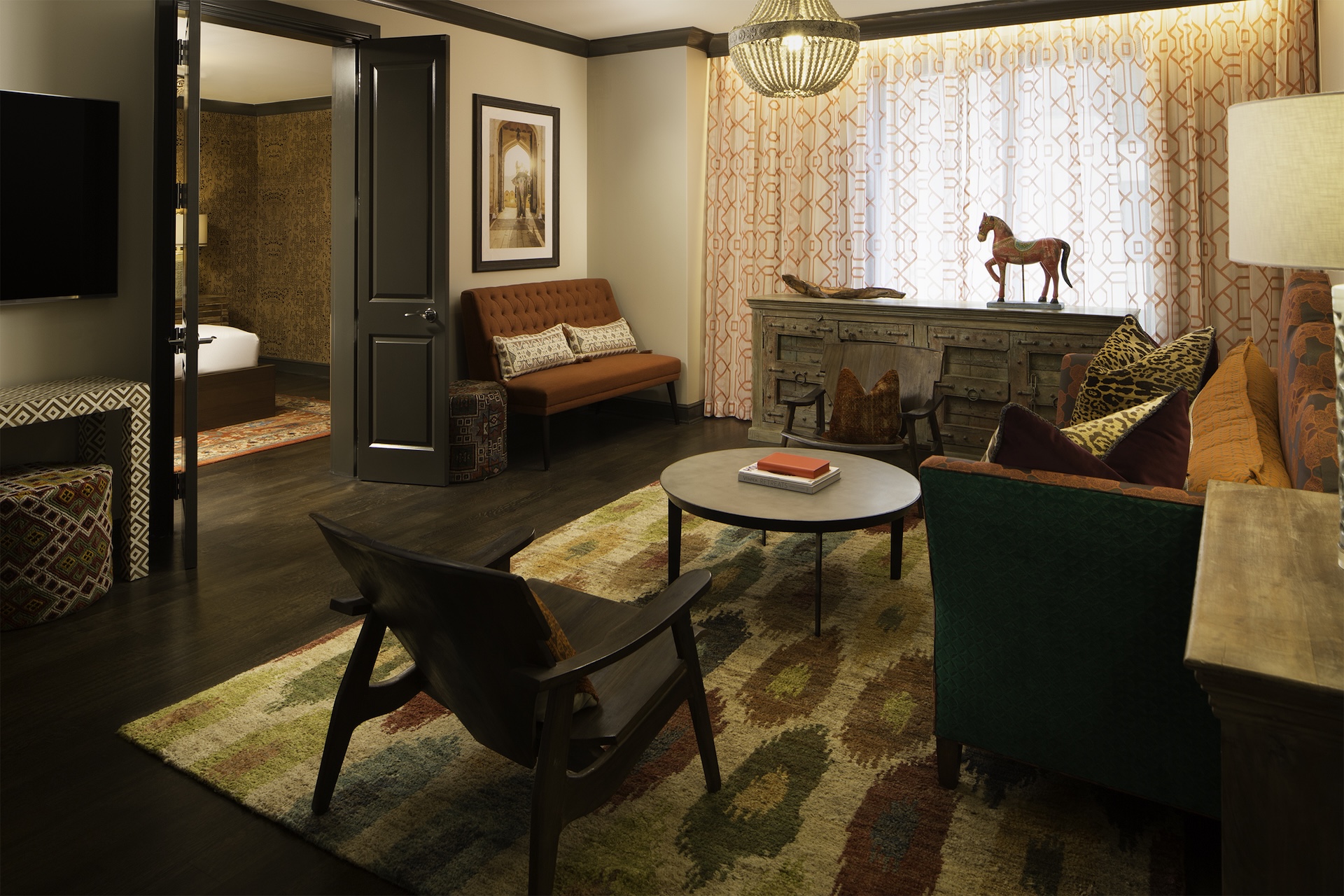 Passage to India suite living room at Hotel ZaZa Memorial with a writing desk, green sofa and patterned rug