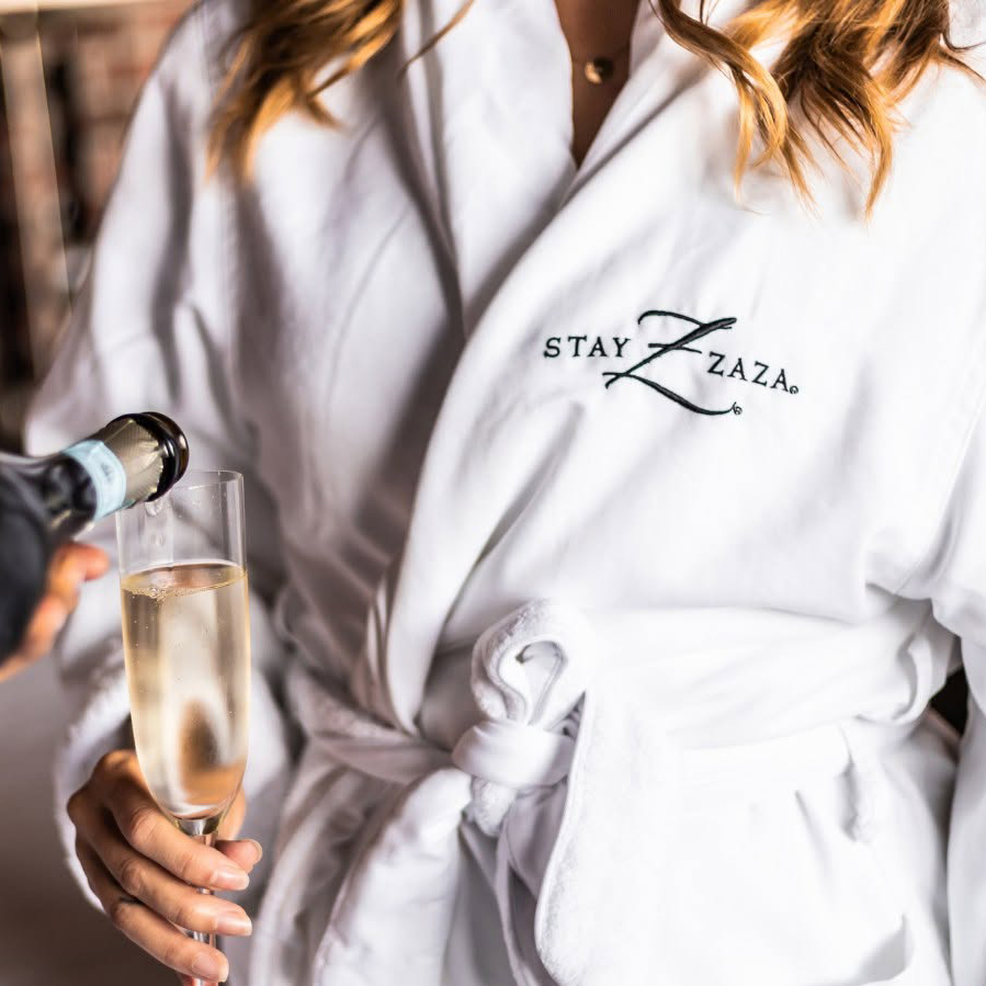 Guest in a Hotel ZaZa robe holding a bottle of champagne and a glass