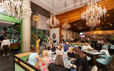 Diners seated at tables in a restaurant at Memorial City Village beneath large ornate chandeliers