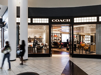 Shoppers passing the Coach storefront inside Memorial City Mall