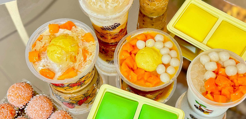Overhead view of bubble tea drinks topped with fruit alongside pastries at M-K-T Heights