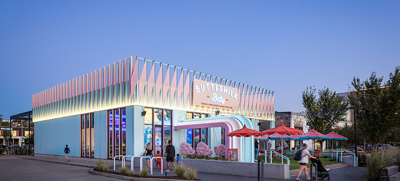 Exterior of Buttermilk Baby at M-K-T Heights, with its scalloped pastel facade and patio umbrellas