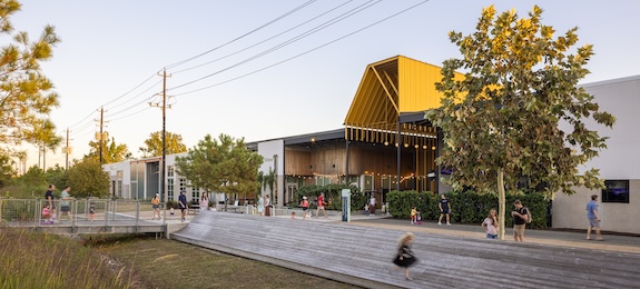 Street view of M-K-T Heights with its angular yellow canopy and people walking the promenade