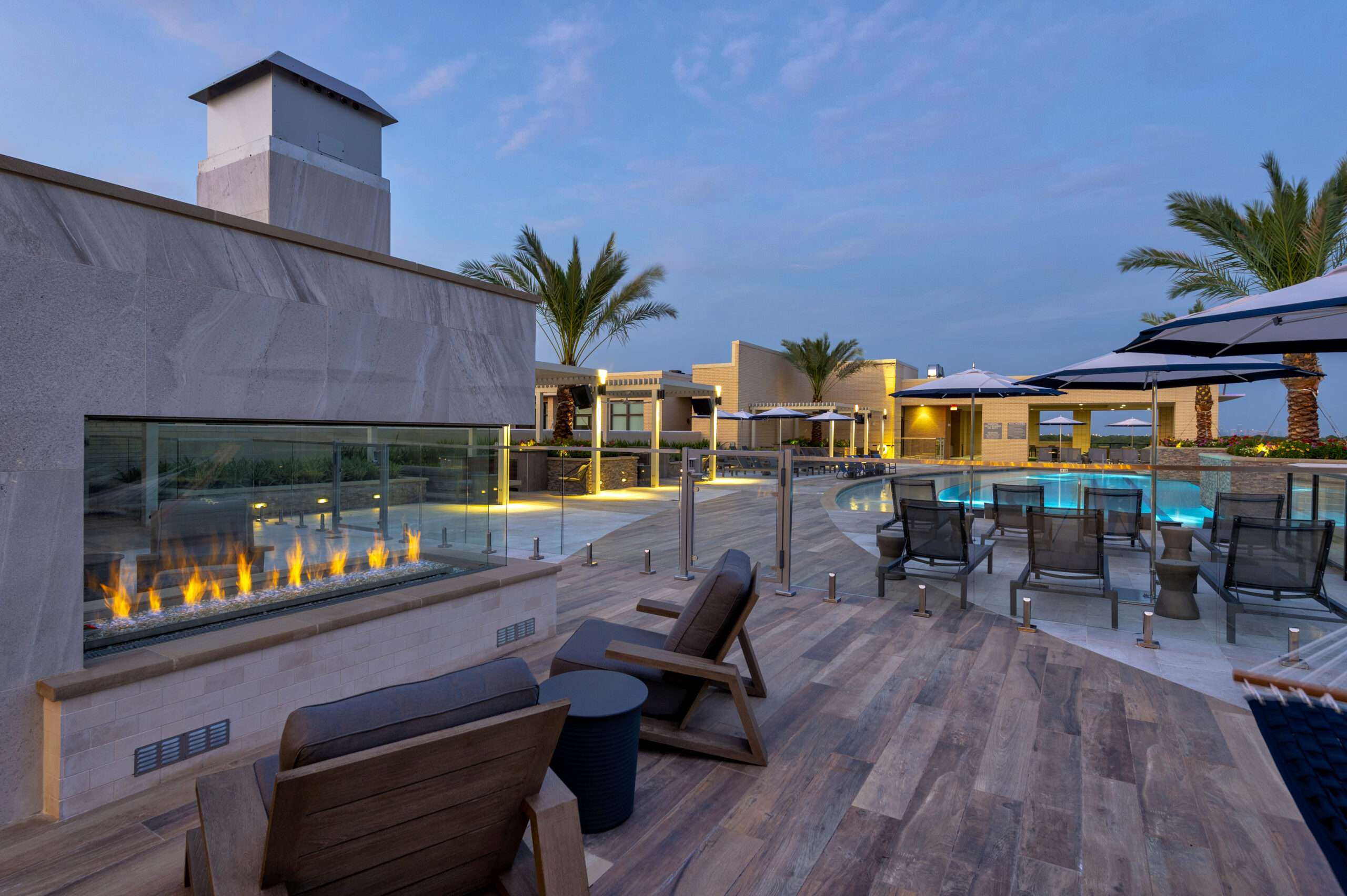 Rooftop lounge at The McAdams with a linear fire feature, lounge seating and palm trees at dusk