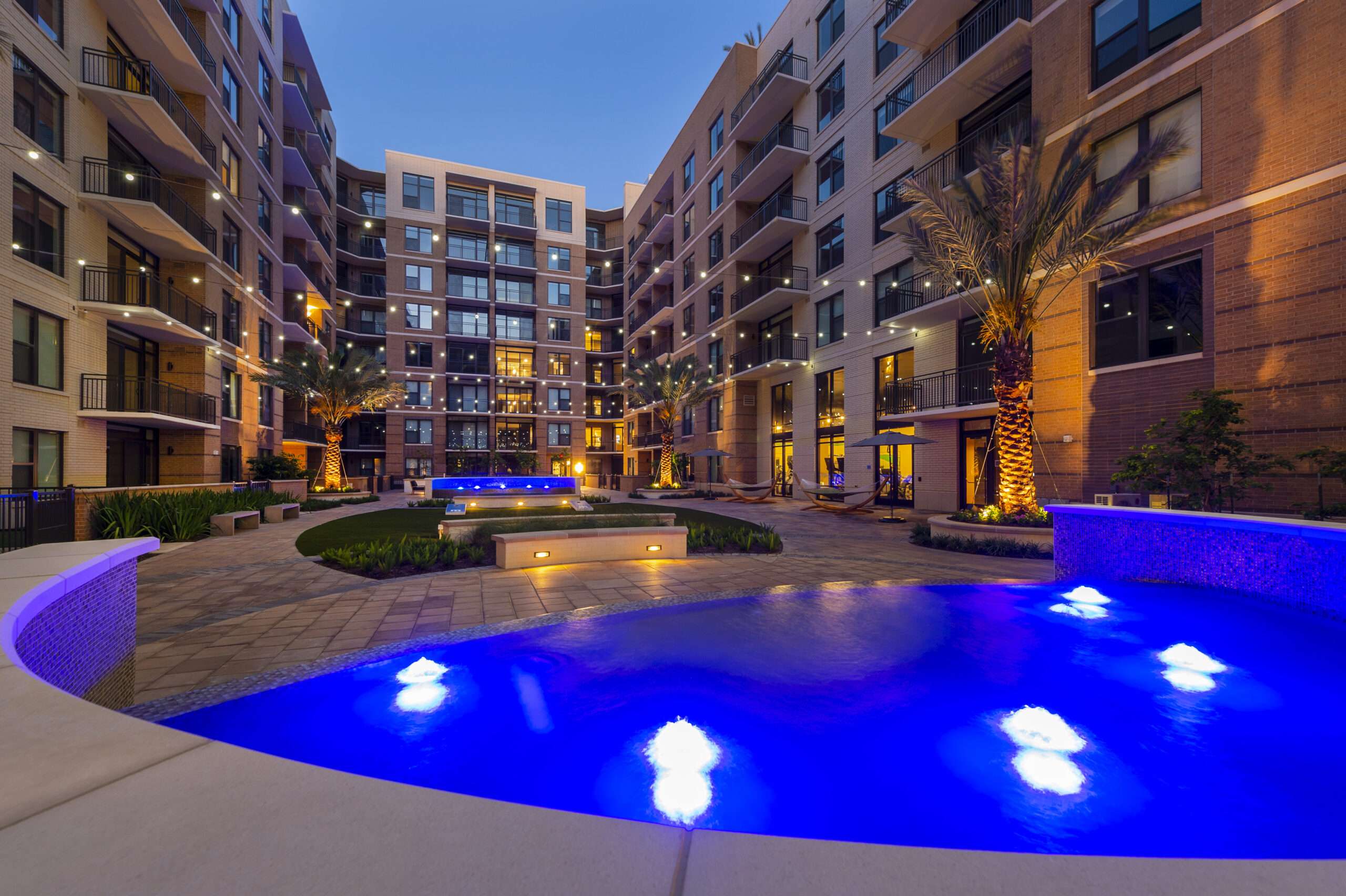 Courtyard pool at The McAdams lit blue at night, with the building wrapping around it