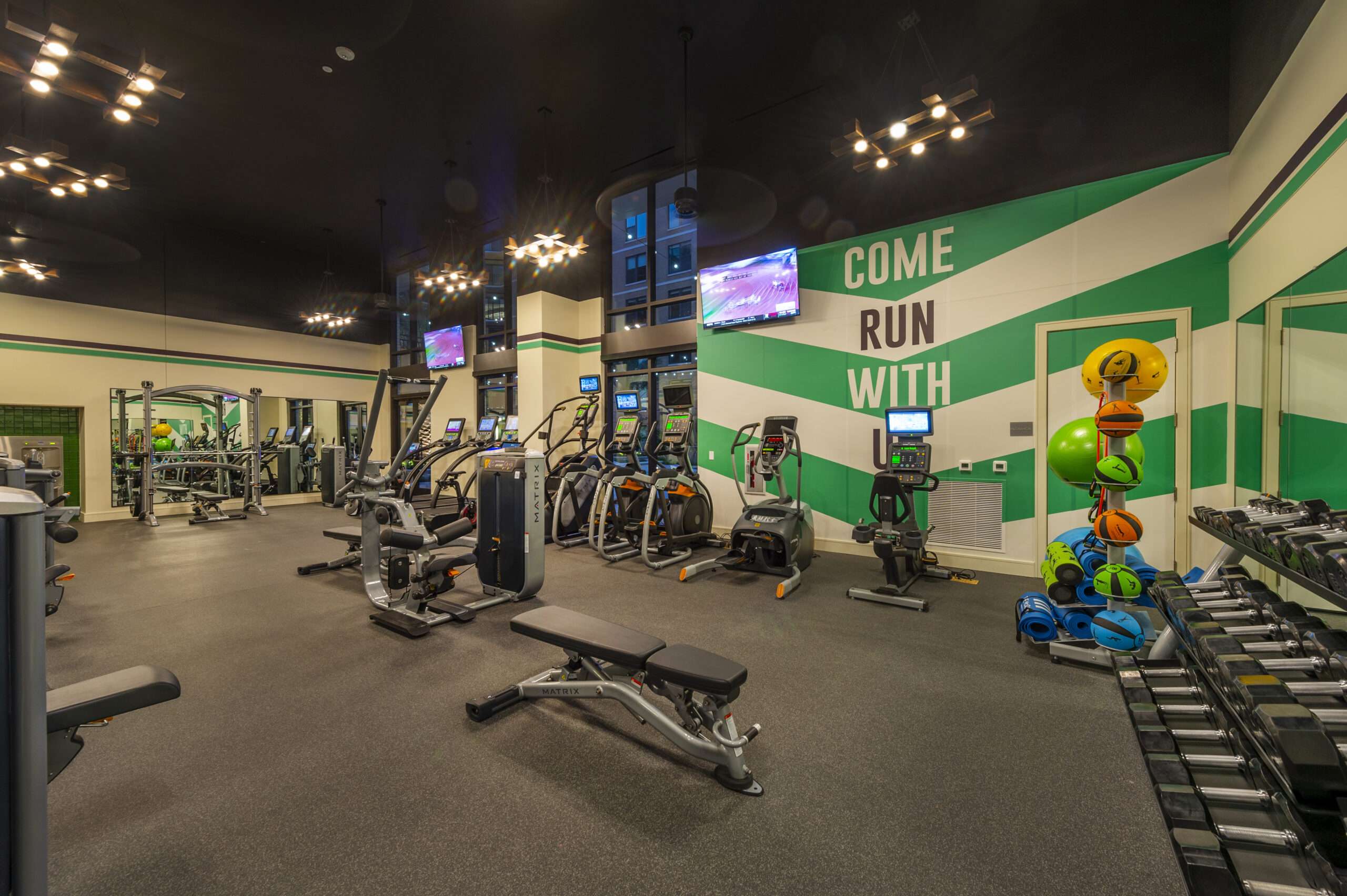 Fitness center at The McAdams with cardio equipment and a green accent wall with painted lettering