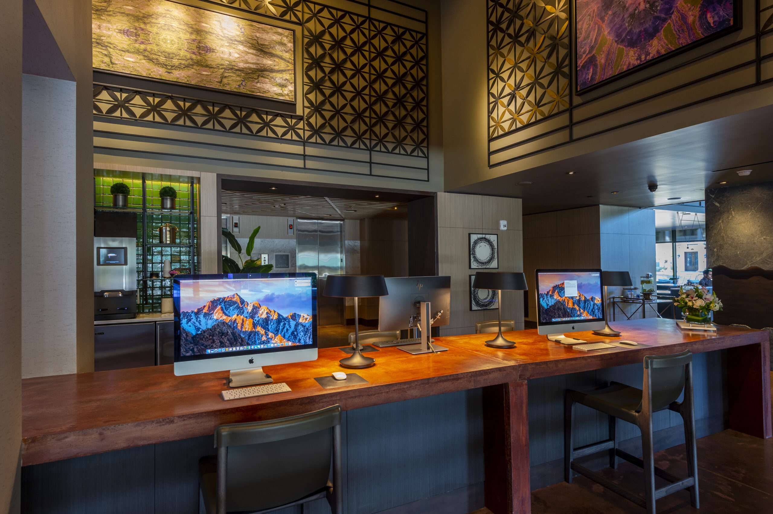 Business center at The McAdams with computers along a wood counter and bar stools