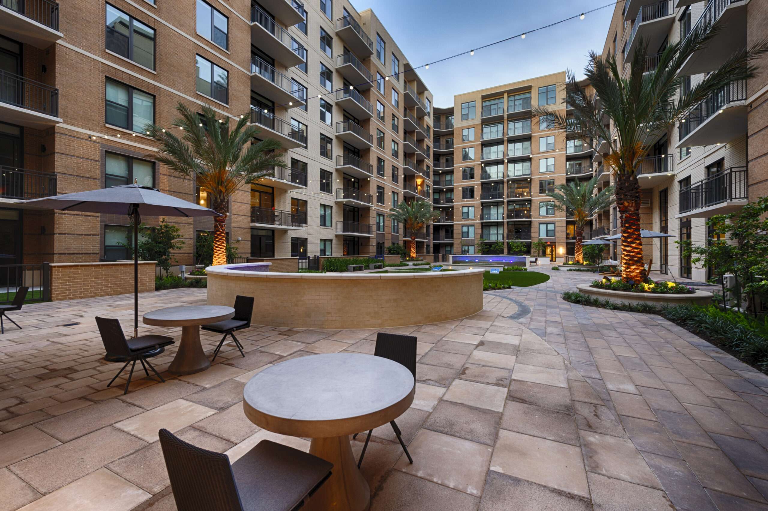 Courtyard seating at The McAdams with cafe tables, an umbrella and palm trees
