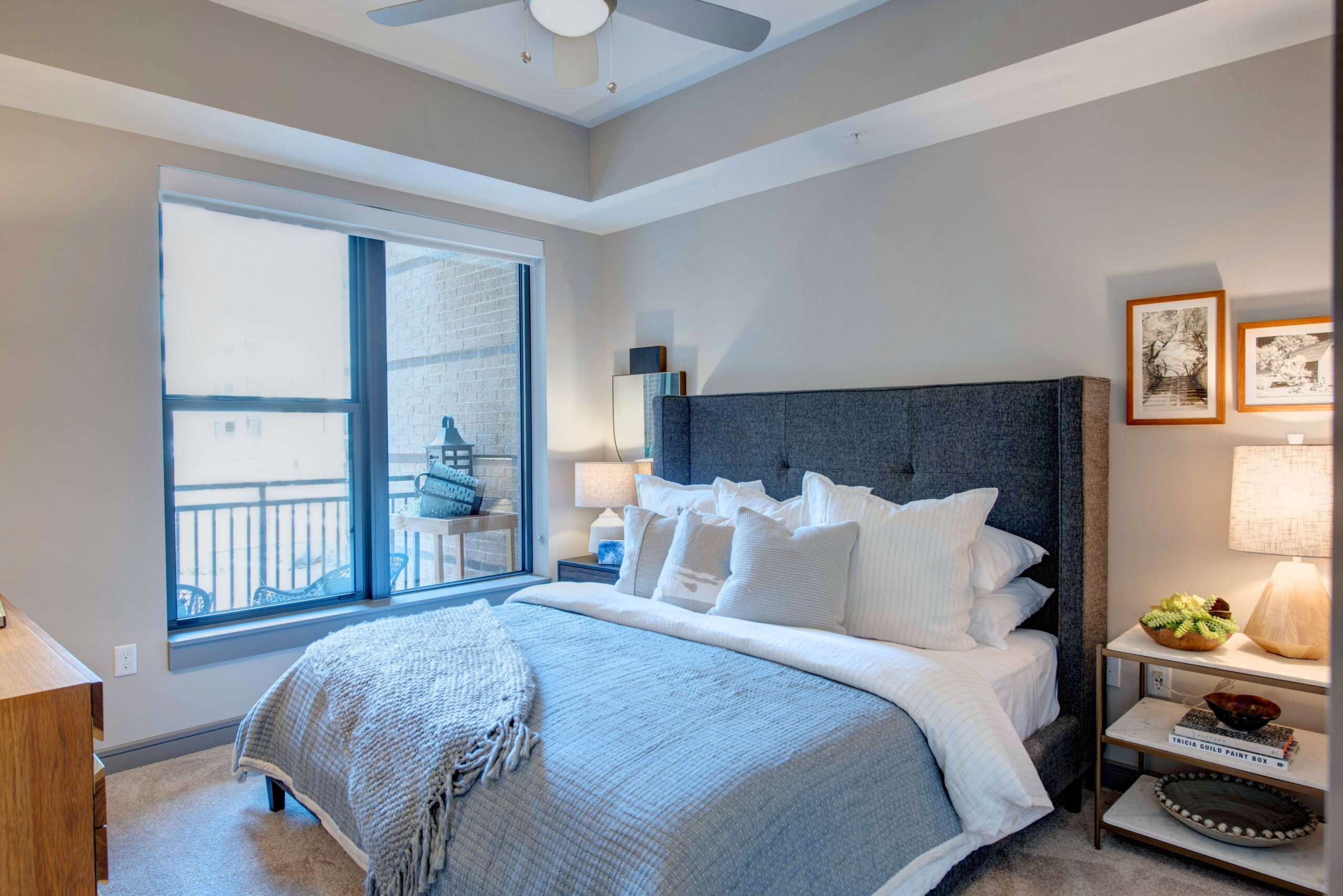 Bedroom at The McAdams with an upholstered headboard, white bedding and a balcony door
