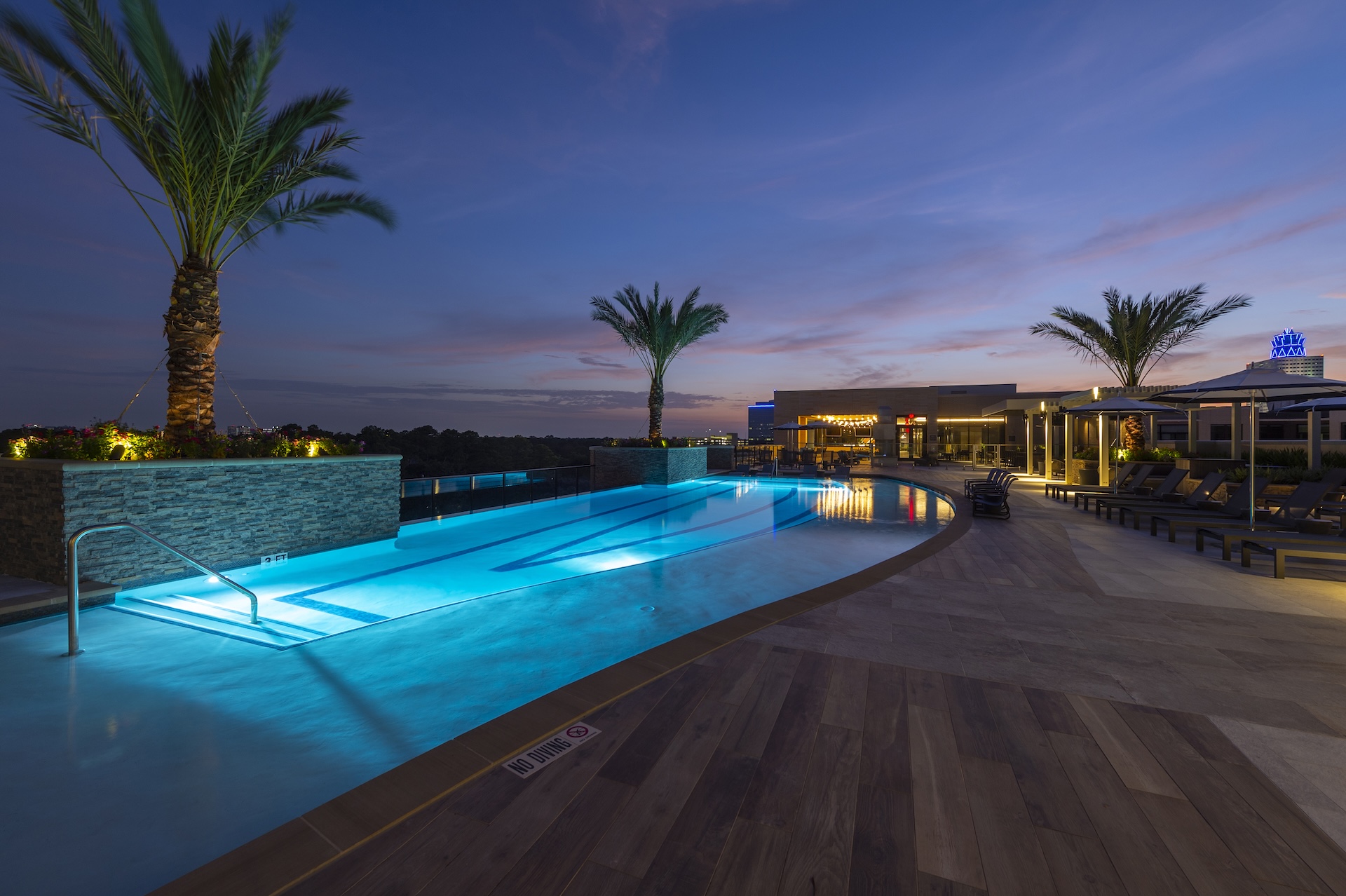 Resort-style pool at The McAdams at dusk, lit from within and framed by palm trees