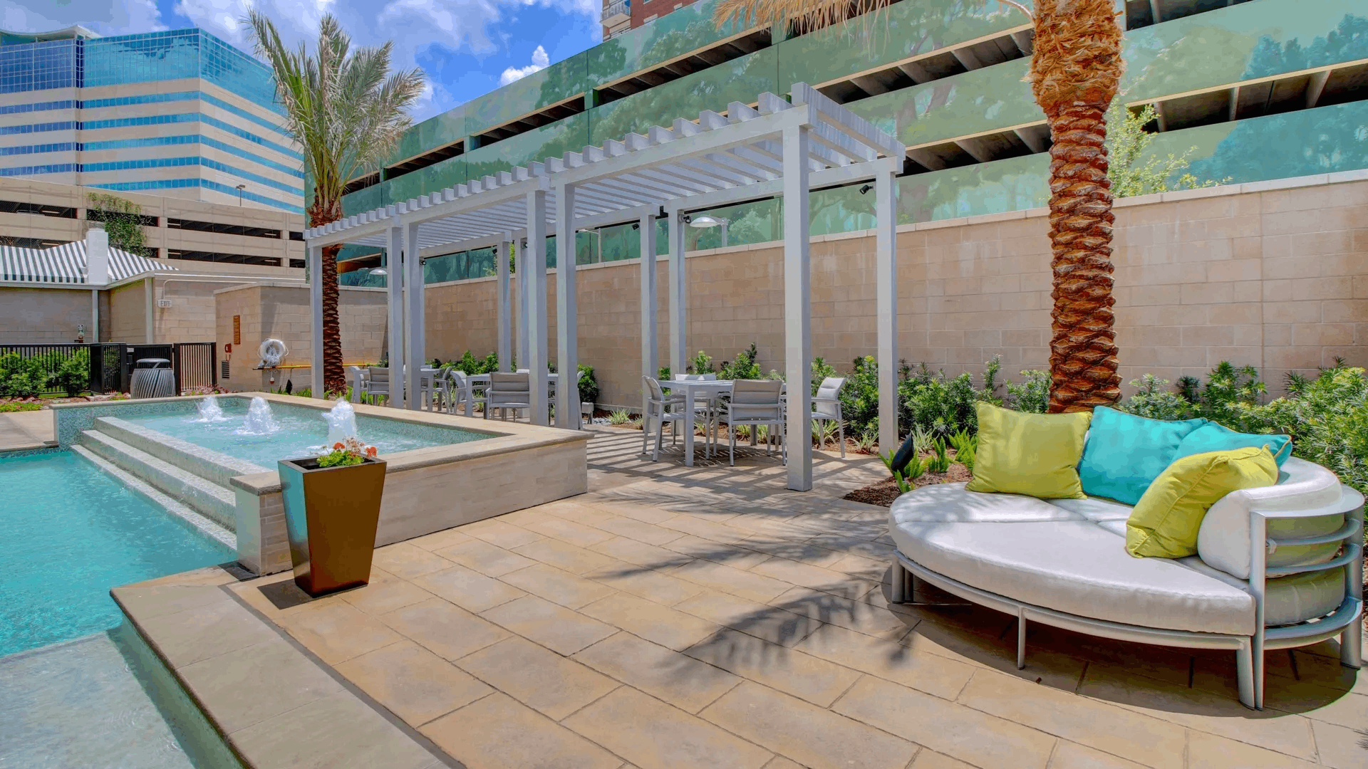 Pool deck at The McCarthy with a pergola, cushioned daybed and palm trees