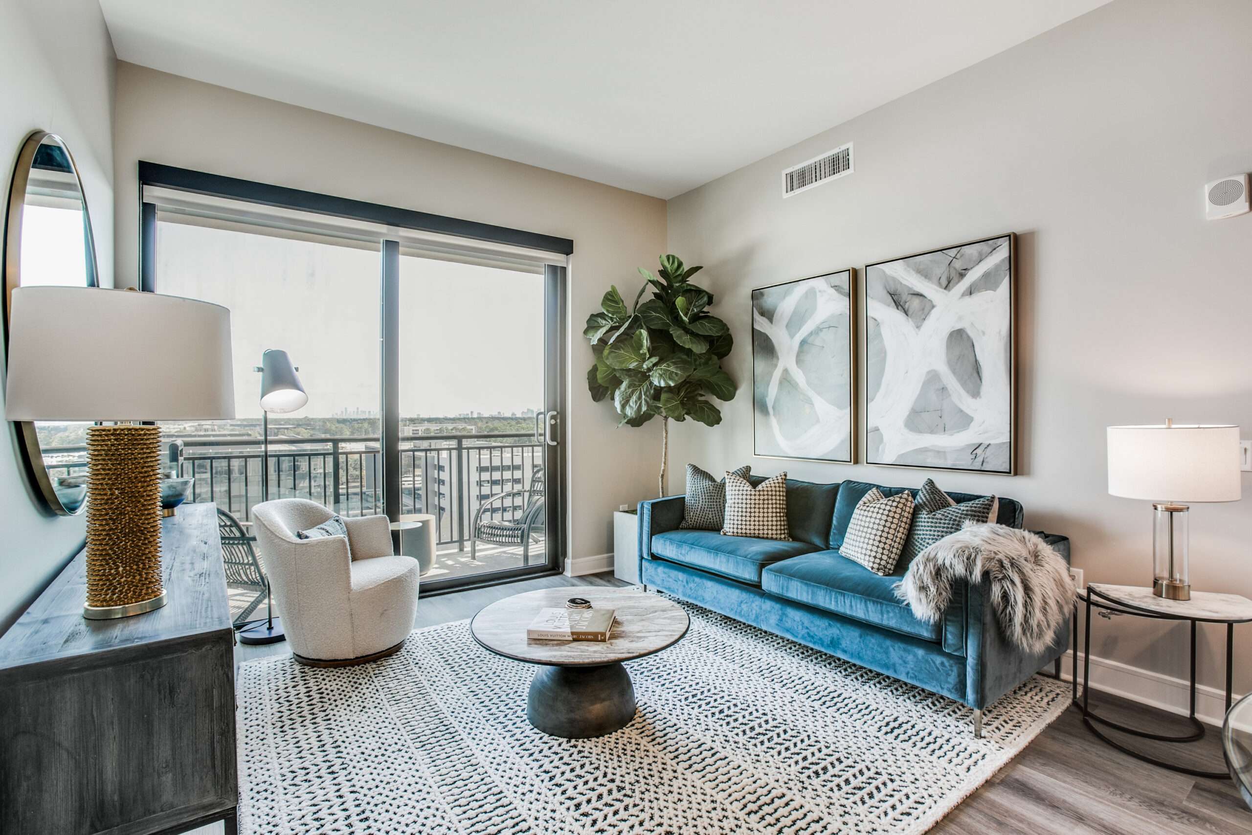 Apartment living room at The McKinley with a teal sofa, armchairs and doors to a balcony