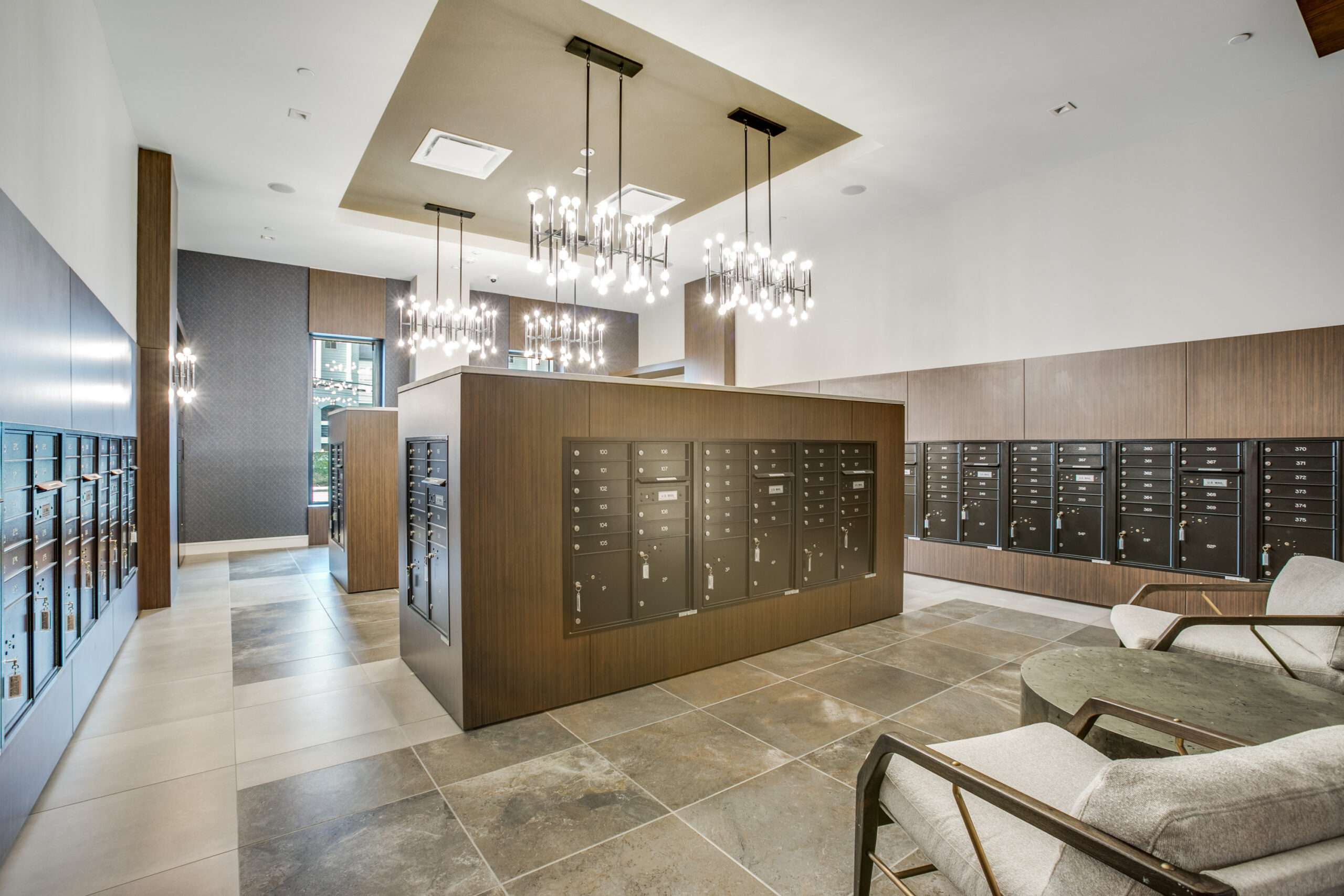 Mail room at The McKinley with resident mailboxes, a chandelier and bench seating