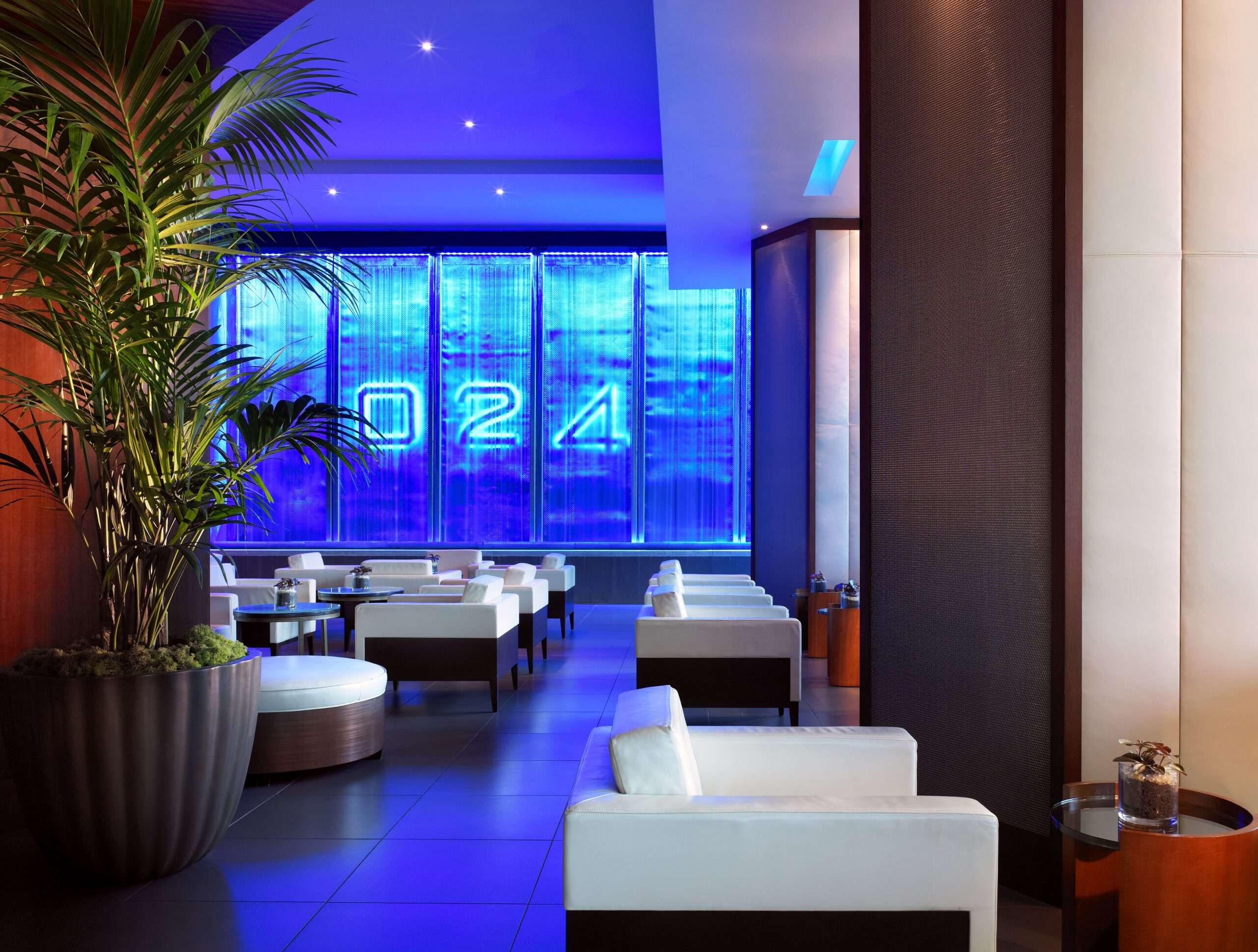 Blue-lit lounge at The Westin Memorial with backlit glass panels, glowing numerals and white seating