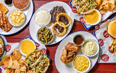 Overhead spread of Tex-Mex plates and side dishes on a red table at Mia’s Table