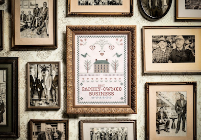 Screenshot 2026-07-22 164553 Gallery wall of framed black-and-white photographs around a framed sampler reading Family-Owned Business