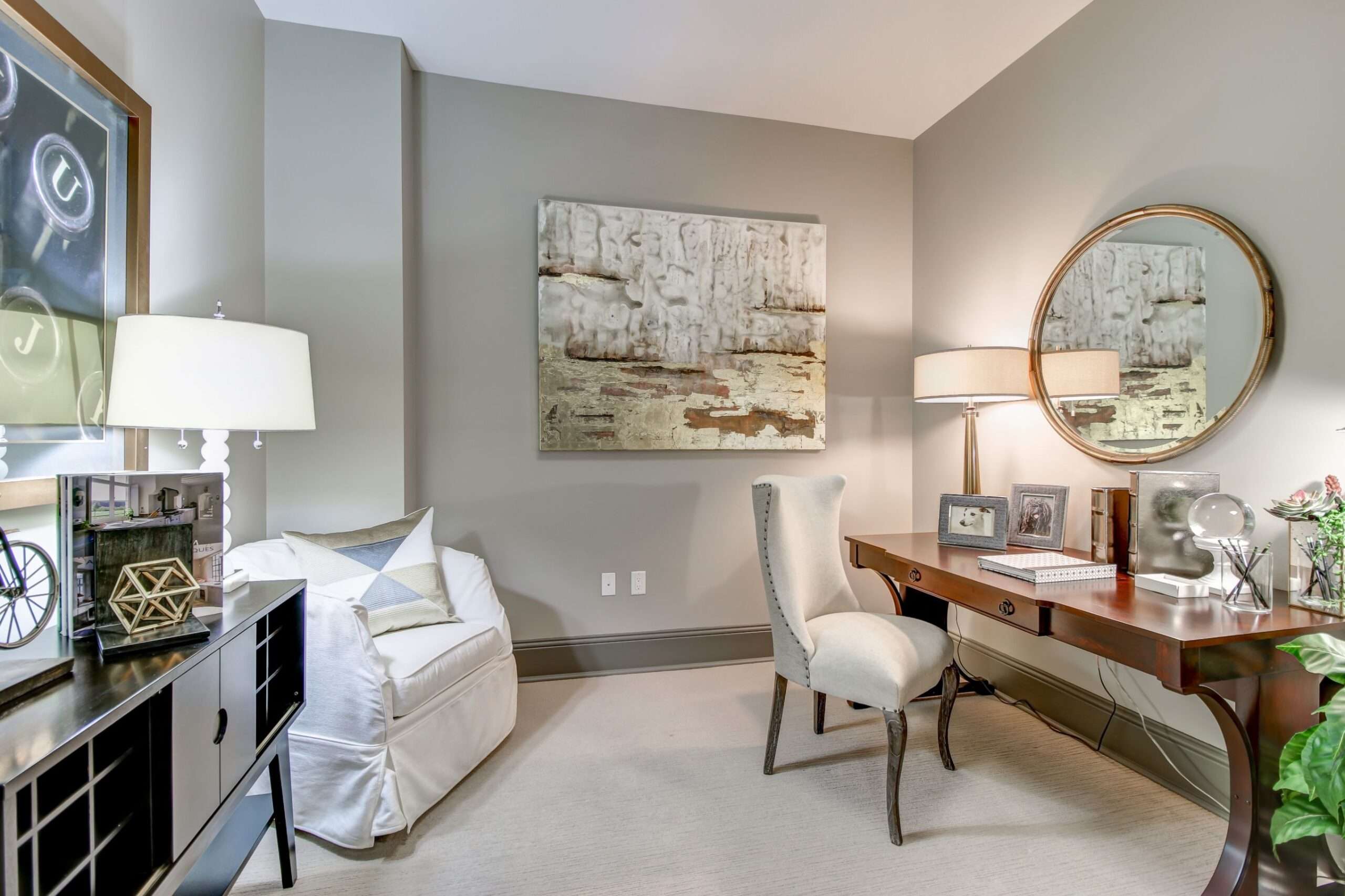Sitting area at The Fountains with a writing desk, round mirror and upholstered chairs