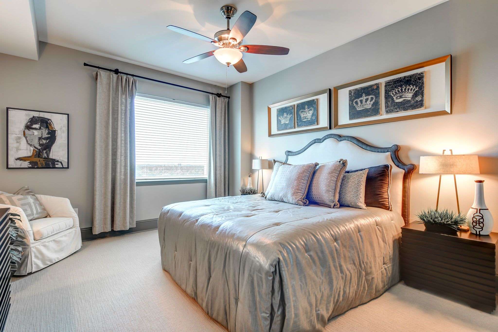 Bedroom at The Fountains with a ceiling fan, framed photographs and a curtained window