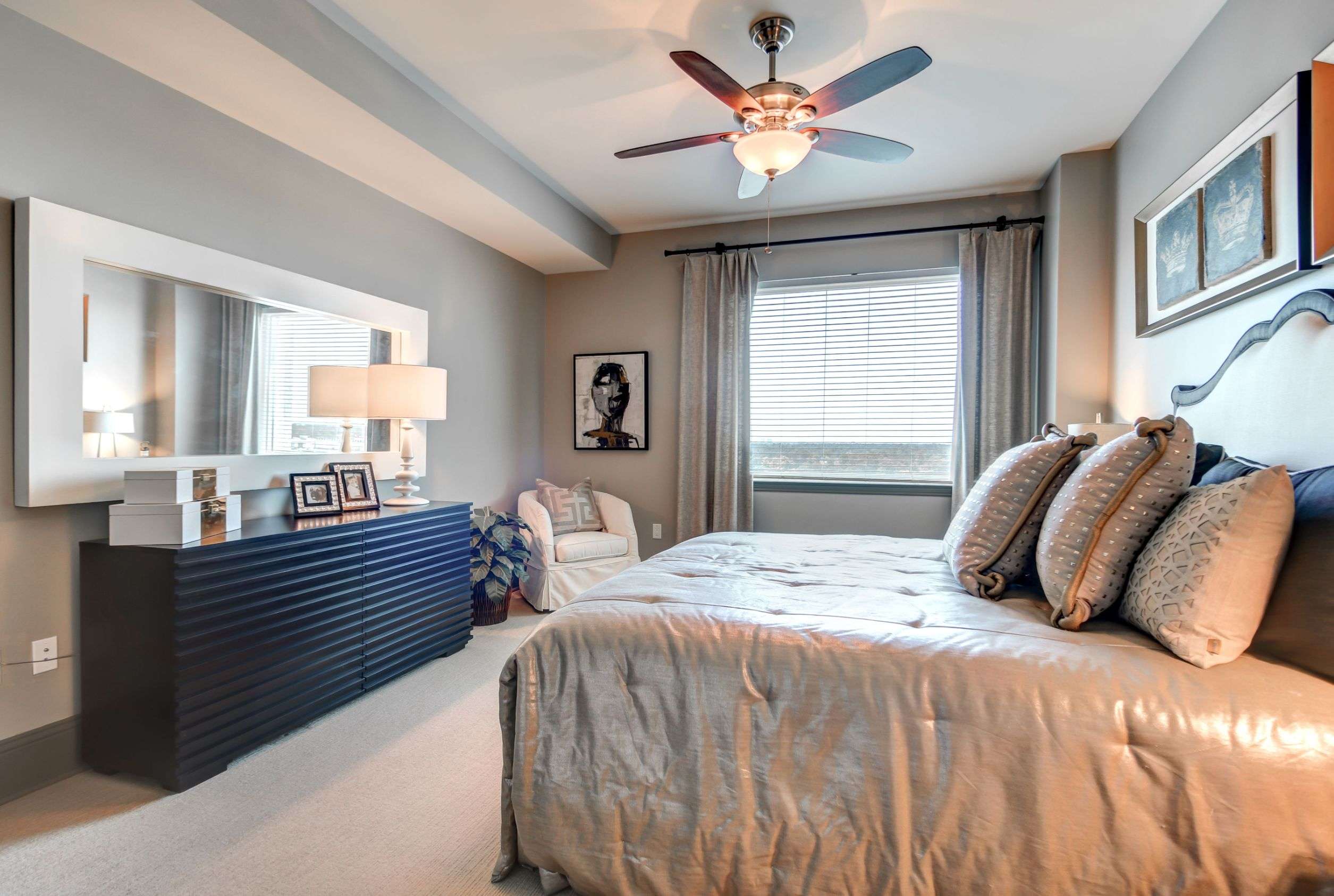 Bedroom at The Fountains with a dresser, bedside lamp and ceiling fan