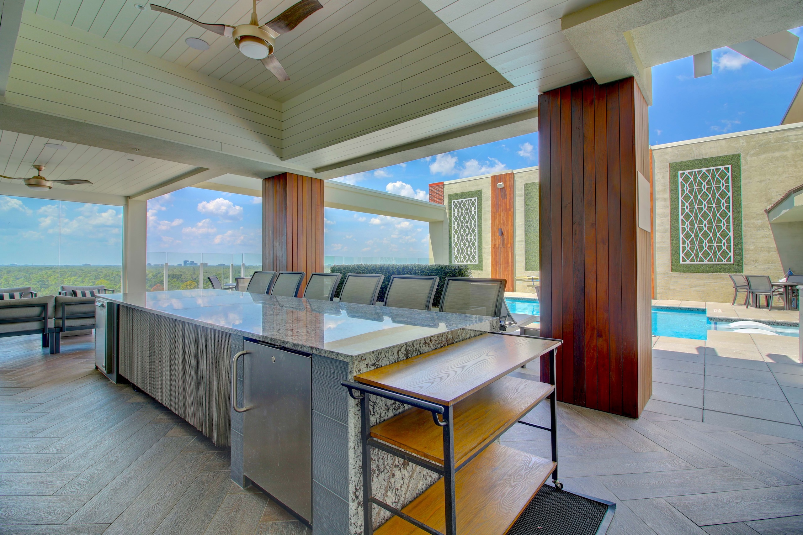 Covered outdoor kitchen beside the pool at The Fountains, with stainless grills and granite counters