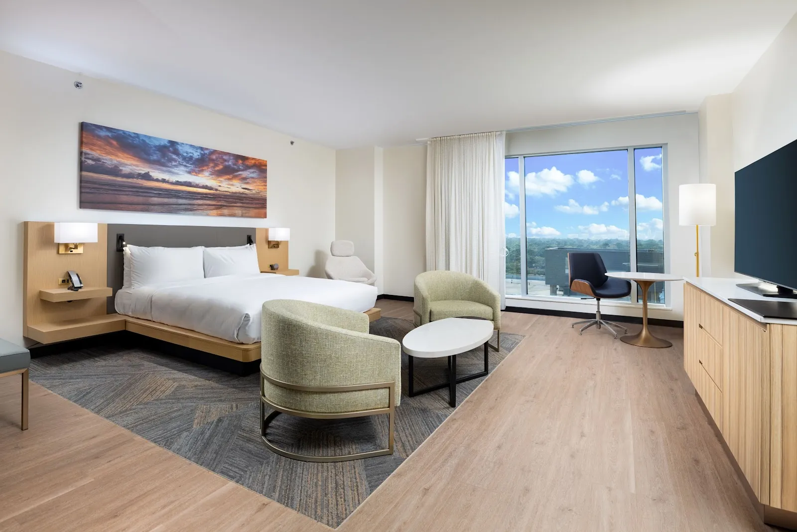 Guest room at The Moran Hotel with a bed, lounge chair, television and sliding door to a balcony