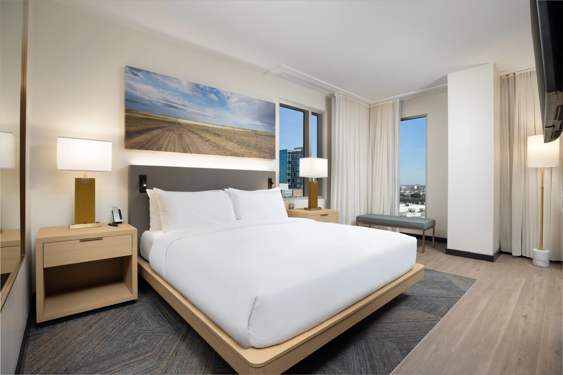 Corner king guest room at The Moran Hotel with windows on two sides and landscape artwork above the bed