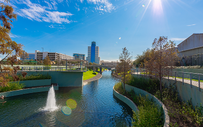 Landscaped waterway with a fountain at Greenside, with office towers rising behind it