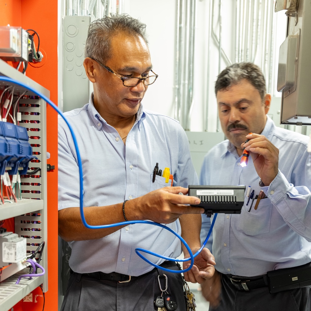 WhyMN-PlaceGrow Two technicians working on network cabling in a MetroNational server room